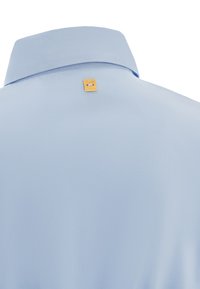 Camicia azzurra con colletto strutturato, caratterizzata da un piccolo etichetta rettangolare dorata sul retro. Tessuto morbido, design semplice.