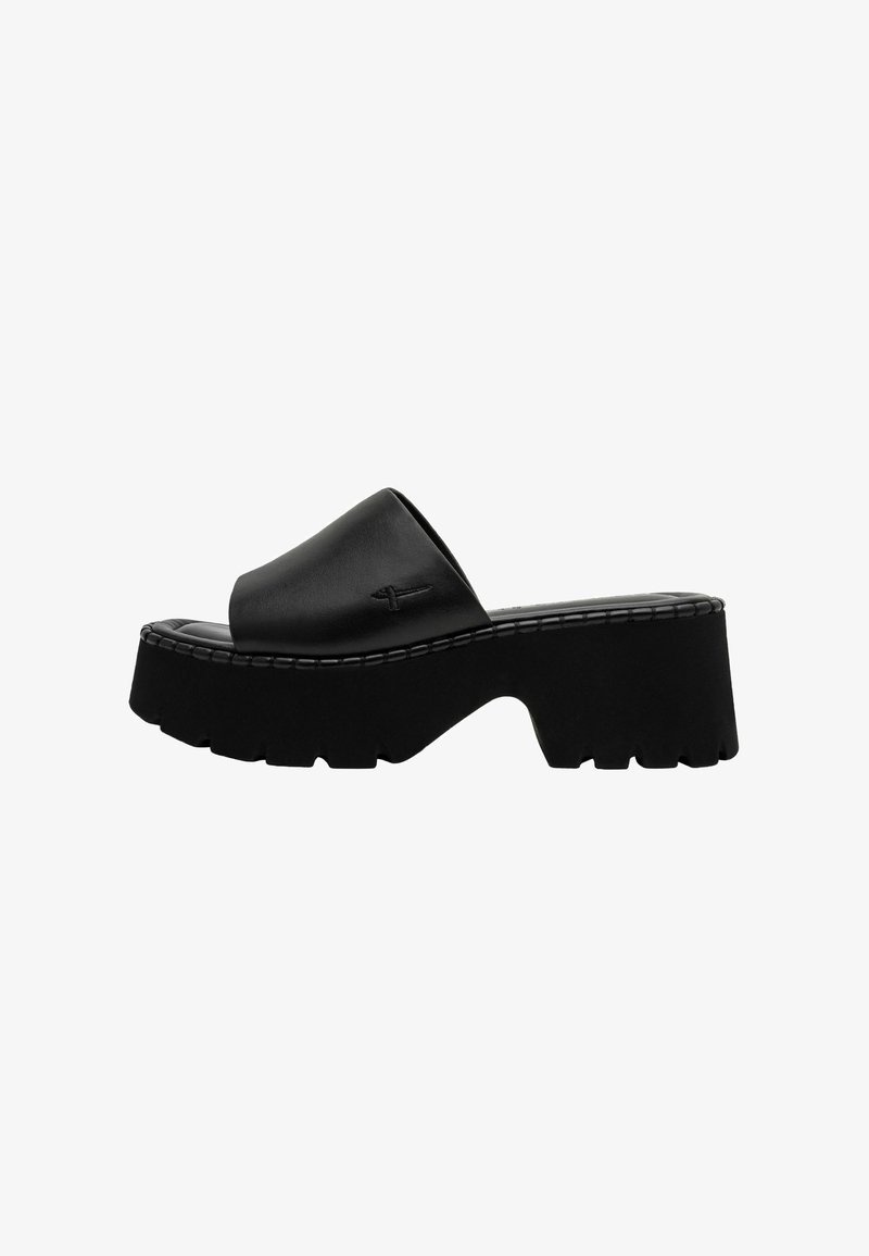 Sandales mules en cuir noir avec une large bride et une semelle épaisse et robuste présentant une texture rugueuse et un design de plateforme prononcé.