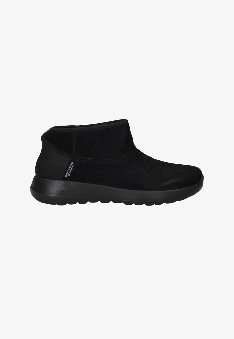 Botines de ante negro con una textura suave, punta redondeada y suela de goma flexible. Presentan un diseño sencillo y estilo slip-on.