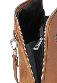 Brązowa skórzana i zamszowa torba z zamkiem błyskawicznym, z czarną podszewką i srebrnymi detalami. Wewnątrz widoczna jest mniejsza kieszeń na zamek.