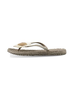 Sandalia tipo chancla plana de tejido beige con suela texturizada y decoración de flor de margarita en las correas marrones y brillantes.
