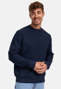 Sudadera texturizada de color azul marino con cuello redondo acanalado, mangas largas y un tejido con patrón. Ajuste casual y material suave.