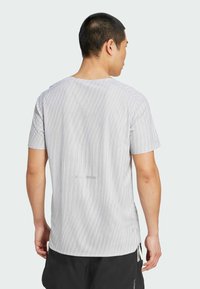 Tričko s krátkym rukávom v svetlosivej farbe s vertikálnymi pruhmi a textúrovanou tkaninou. Disponuje zaobleným výstrihom a jemným logom na zadnej strane.