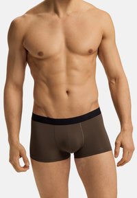 Boxer briefs marroni da uomo con un elastico nero in vita, caratterizzati da una texture liscia e una vestibilità aderente, esposti su un torso nudo.