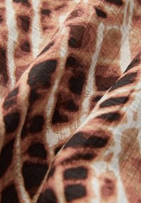 Material cu imprimeu de leopard maro și negru, cu textură și pliuri vizibile.