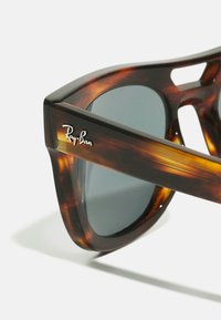 Tortoiseshell Ray-Ban solbriller har en tykk plastinnfatning, grå linser og en sølvlogo på stangen, som forbedrer den karakteristiske designen.