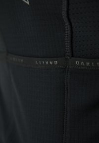 Black athletic shirt featuring textured fabric, seamless design, and an elastic waistband with "Oakley" and "Parkaity" branding.