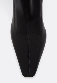 Stivale alla caviglia nero con punta appuntita, tessuto morbido, cuciture visibili e una silhouette elegante senza hardware o accenti.