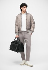 Jachetă bomber matlasată gri, polo alb, pantaloni de trening gri, geantă de voiaj din piele neagră și adidași cu platformă crem. Design simplu și funcțional.