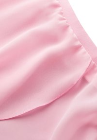 Rosa Stoff mit einer glatten, weichen Textur, der an einer Kante geraffte Rüschen aufweist und einen subtilen Glanz hat. Die Naht ist in einem kontrastierenden hellrosa Farbton.