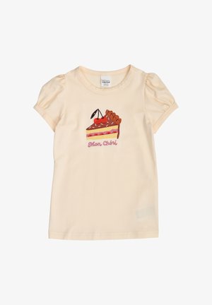 Kremowa koszula dziewczęca z krótkimi bufkami na rękawach, z haftowanym tortem z wisienką na górze i napisem „Mon Chéri” poniżej.