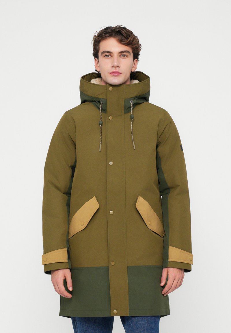 Parka vert olive avec une capuche, accents beige contrastants sur les poches et les poignets, boutons-pression et finition en tissu texturé.