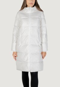 Piumino bianco con chiusura con zip, cappuccio e due tasche laterali. Design trapuntato con texture liscia, che arriva fino al ginocchio.