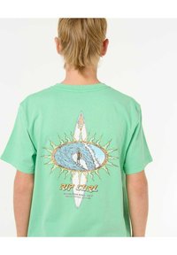 Camiseta de algodón verde claro con un diseño gráfico de un surfista dentro de una ola, rodeado de rayos de sol; texto "Rip Curl" en la parte inferior.
