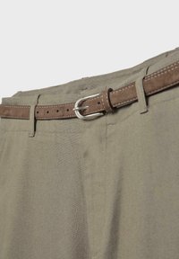 Close-up of khaki pants waist with a brown suede belt threaded through loops, fastened with a silver metal buckle.