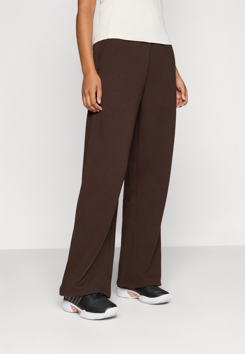 Brown wide-leg pants made of soft fabric, featuring a smooth texture and a relaxed fit, paired with black athletic shoes.