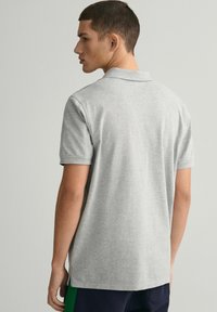 Grå kortermet polo skjorte med en myk tekstur, med en klassisk krage og et ensfarget design. Nederkant med trim og sidespalter.
