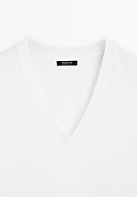 Weißes Baumwoll-T-Shirt mit V-Ausschnitt und kurzen Ärmeln aus weichem Material. Verfügt über ein schwarzes Etikett mit dem Schriftzug "Massimo Dutti". Einfaches Design, ohne Muster.