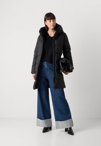 Black puffer coat with a hood, paired with wide-leg blue jeans featuring frayed cuffs and a black clutch bag. Smooth, glossy texture.