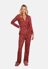 Roter Blumenpyjama bestehend aus einem Wickeloberteil mit langen Ärmeln und einem Bindeband in der Taille, kombiniert mit lockeren Hosen. Weicher Stoff, für besonderen Komfort entworfen.