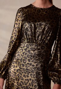 Leopardenmuster Kleid aus metallisch goldenem und schwarzem Stoff. Verfügt über lange Ärmel und eine geraffte Taille für eine figurbetonte Silhouette.
