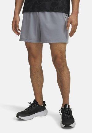 Grå atletiske shorts med en glat, let tekstur, parret med sorte løbesko med en hvid sål og reflekterende detaljer.