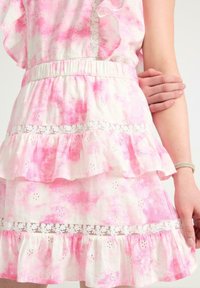 Abito rosa tie-dye con strati arruffati, vita elastica, dettagli ricamati e un bordo in pizzo all'orlo. Tessuto leggero.