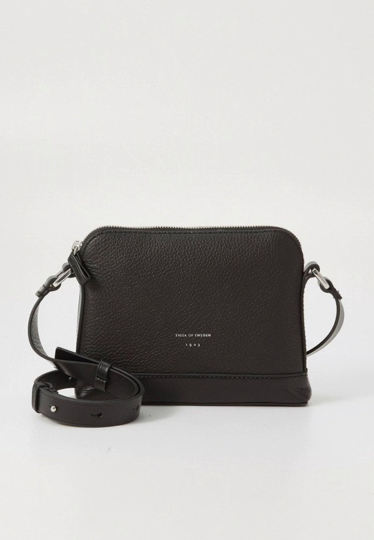 Sac bandoulière en cuir noir avec surface texturée, ferrures argentées et une sangle amovible. Doté d'une fermeture éclair et d'un détail de marque.