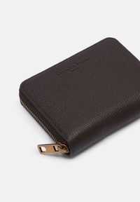 Ciemnobrązowy portfel z skóry o ziarnistej fakturze, z złotym suwakiem i tłoczonym logo marki na powierzchni. Kompaktowy, prostokątny kształt.