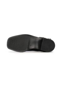 Suela de zapato negra con una superficie de goma texturizada con un patrón de diamantes para mayor tracción, y parte superior de cuero suave con una correa ajustable.