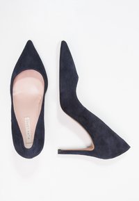 Sjöblå mocka högklackade skor med spetsig tådesign, slätt innerfoder och stängd baksida; smal stilettklack för extra höjd.