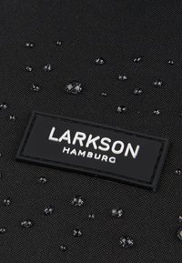Čierna textúrovaná tkanina s vodotesnou úpravou, zdobená kvapkami a čiernym logom s nápisom "LARKSON HAMBURG."