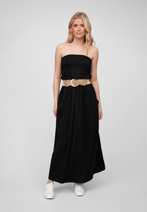 Svart stroppeløs maxikjole med sidelommer, innsvingt liv med et brunt belte med sirkulær spenne, kombinert med hvite joggesko.