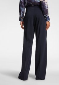 Pantalones de pierna ancha de color marino, hechos de una tela suave, con una cintura ajustada y un corte limpio, mostrados desde la parte trasera con un mínimo de detalles.