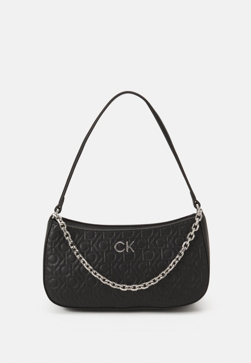 Sac à épaule noir avec motif du logo CK embossé, emblème CK argenté et une chaîne décorative argentée sur le devant.