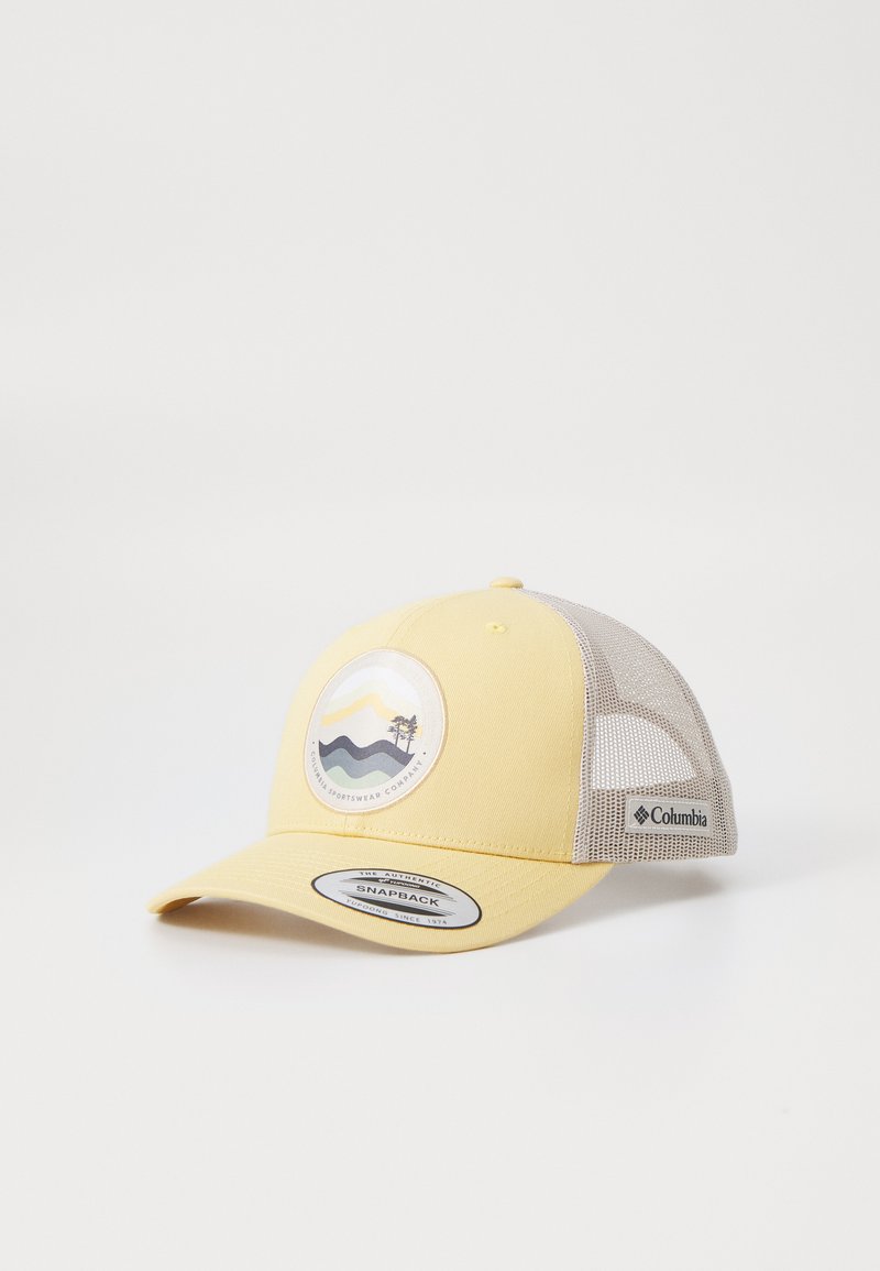 Geel snapback pet met een mesh achterkant, voorzien van een circulair logo dat golven en een boom weergeeft in gedempte kleuren. Columbia branding aan de zijkant.