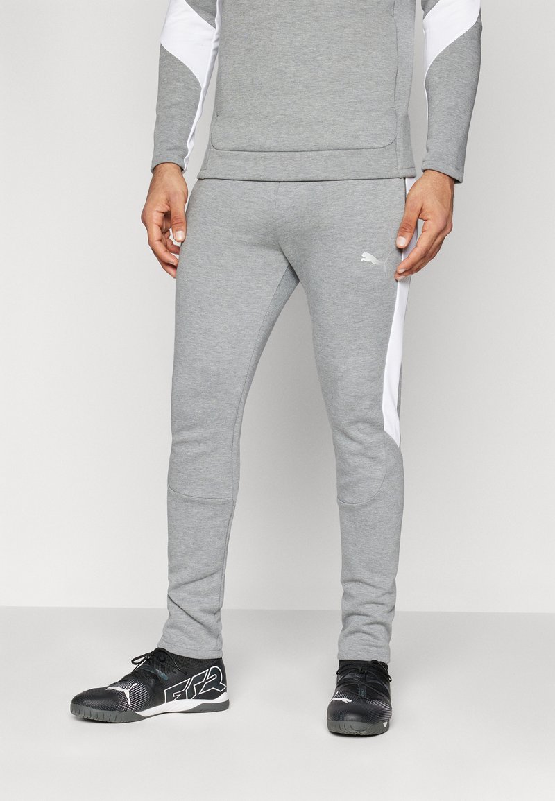 Grå træningsbukser med hvide sidelofar, der har en slim fit, blød tekstur og et lille logo på fronten af hoften. Sæt sammen med sorte sportssko.