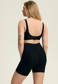 Black sports bra and high-waisted shorts set, seamless design, stretchy fabric, featuring back closure and decorative stitching details.