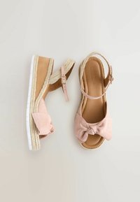 Růžové semišové espadrilky na sandály s mašlí, tkanou texturou, nastavitelným popruhem kolem kotníku a silnou bílou podrážkou.
