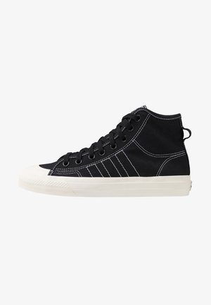 Black high-top sneakers made of canvas with white stitching, rubber toe cap and sole, featuring eyelets and a heel loop for easy wear.
