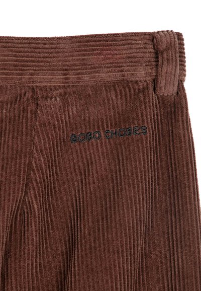 Tissu en velours côtelé brun foncé avec des côtes verticales, montrant une ceinture et une boucle, avec un texte brodé en noir "BOBO CHOSES."