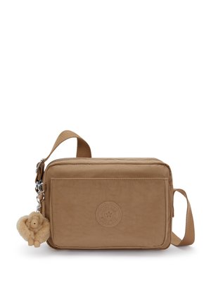 Small rectangular tan crossbody bag with front zip pocket, adjustable strap, and fluffy monkey keychain attached to side zipper.