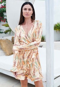Wickelkleid mit floralem Muster in Orange, Braun und Grün. Verfügt über lange Ärmel und einen rüschend gesäumten Saum. Aus leichtem Stoff gefertigt.