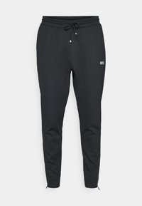 Črne trenirke iz mehkega materiala, z vrvico v pasu, stranskimi žepi in slim fit dizajnom z zadrgama pri gležnjih.