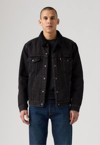 Zwarte denimjack met een sherpa-kragen, voorzien van een knoopsluiting aan de voorkant, twee borstzakken en een relaxte pasvorm. Draag het over een zwart T-shirt.