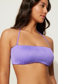 Fioletowy biustonosz bikini z fakturowanym wzorem fal, z cienkimi regulowanymi ramiączkami i bezszwowym wykończeniem. Gładki, elastyczny materiał.