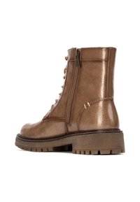 Bota de tobillo de cuero marrón con acabado brillante, con cordones en la parte delantera, cremallera lateral y suela robusta con tacos pronunciados. Decorada con herrajes en tono dorado.