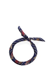 Bufanda de seda azul marino con un patrón decorativo en tonos rojos y dorados, retorcida y atada en un nudo, forma circular.