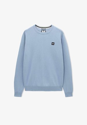 Lichtblauwe crewneck trui met lange mouwen, ribbels aan de mouwen en onderkant, en een klein zwart vierkant logo op de linkerkant van de borst.