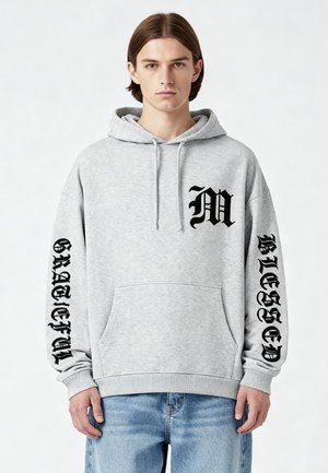 Grijze hoodie van fleece met een kangoeroezak. Bevat zwarte bedrukte tekst "M" en "GRATEFUL" op de mouwen en "BLESSED" op de borst.